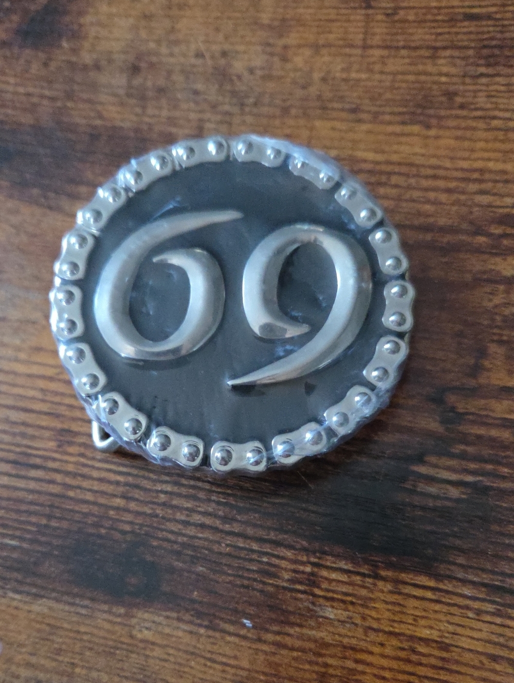 circular belt buckle features a bold silver number "69"